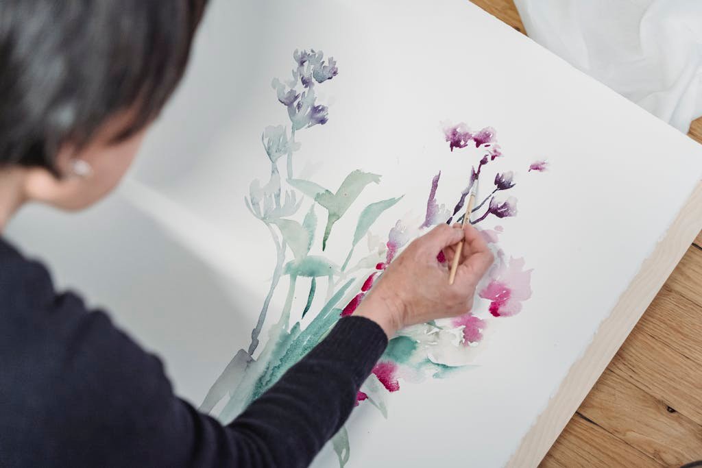Close-up of artist painting floral watercolor illustration with a brush. Creative and vibrant art.